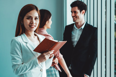 Happy young beautiful businesswoman reading book and working in office with colleagues and friend at workplace. Corporate business people group. udsの写真素材