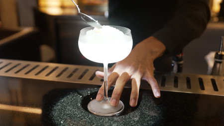 Closeup hand bartender adding sugar or salt to mixed vodka cocktail glass, preparation making special drink menu to VIP guest at front bar luxury. Special refresh drink showcasing nightlife. Vinosity.の写真素材