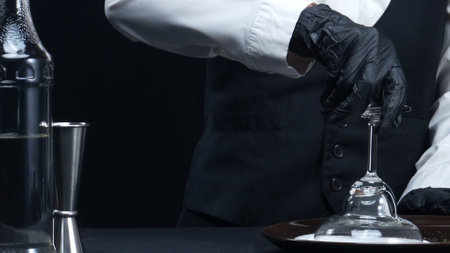Professional bartender making fresh margarita with salted garnish glass. Macrography of skilled bartender hands prepare for making cocktail with black background at the bar. Slow motion. Comestible.の写真素材