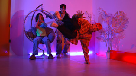 Happy hipster show break dancing while multicultural friend with casual cloth cheering at studio. Professional street dancer perform hip hop beat or lively rhyme with neon or led light. Regalement.の写真素材