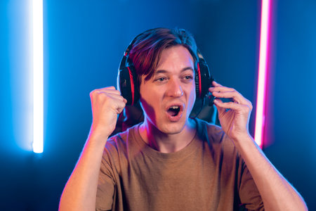 Host channel of gaming smart streamer playing online game to be winner, wearing headphone with viewers live steaming on media social online for selected team competition at neon light room. Pecuniary.の写真素材