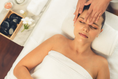 Panorama top view of woman enjoying relaxing anti-stress head massage and pampering facial beauty skin recreation leisure in dayspa modern light ambient at luxury resort or hotel spa salon. Quiescentの写真素材