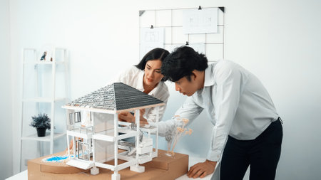 Closeup of young professional skilled architect engineer team focusing on checking the house model structure at modern office. Creative professional design and teamwork concept. Immaculate.の写真素材