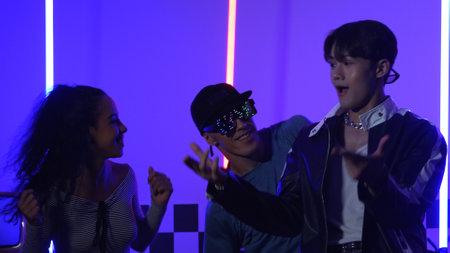 Happy hispanic girl with casual shirt dancing together with diverse break dancer with neon light. Professional street dancer moving to freestyle music with led light at house and party. Regalement.の写真素材