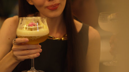 Closeup beautiful woman making a toast mixed passion fruit smoothie cocktail with friend holding glass in coconut smooth fizzy drink at nighttime warm light at nightclub counter bar party. Vinosity.の写真素材