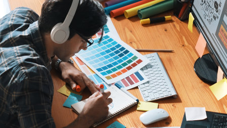 Interior designer looking at laptop and designing color while looking at palette at meeting table with laptop, computer and paper placed. Close up of business man working on color design. Symposium.の写真素材