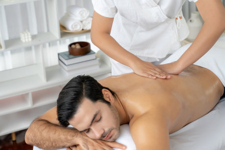 Caucasian man customer enjoying relaxing anti-stress spa massage and pampering with beauty skin recreation leisure in day light ambient salon spa at luxury resort or hotel. Quiescentの写真素材