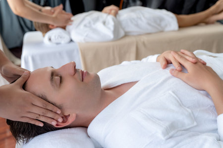 Caucasian couple enjoying relaxing anti-stress head massage and pampering facial beauty skin recreation leisure in dayspa modern light ambient at luxury resort or hotel spa salon. Quiescentの写真素材