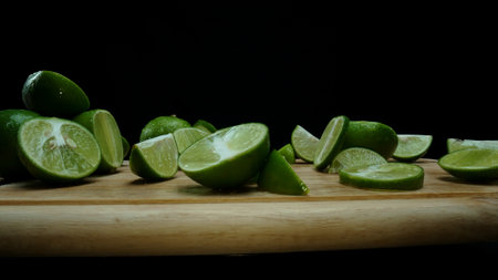 Close-up, a vibrant slice of fresh lime rests upon a rustic wooden cutting board, exuding freshness and vitality. The translucent membranes of the green lime slice placed on cutting board. Comestible.の写真素材