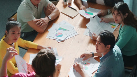 Top down view of start up business team holding paper while discussing about financial idea. Aerial...