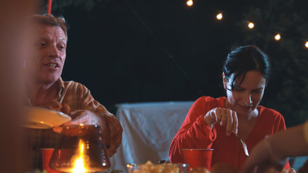 Generous grandmother together with family celebrate holiday in garden eat dinner food. Outdoor...