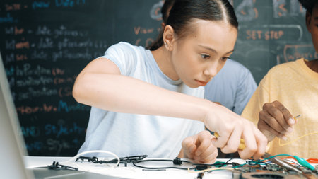 Happy highschool student using electronic tool fixing board while caucasian teacher help preparing...