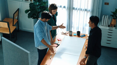 Top view of smart business team explain and discuss about plan at meeting table with sticky notes. Group of diverse people brainstorming idea at boardroom while standing at meeting table. Convocation.の写真素材