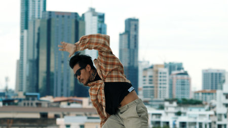 Hispanic break dancer practice B-boy footsteps at roof top with urban city view or sky scrapper....
