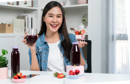 Smiling young beautiful Asian reviewing tasty mixed strawberry and cherry juice detox drinks, showing healthy product to promote for special promotion selling on social media online record. Stratagem.の写真素材