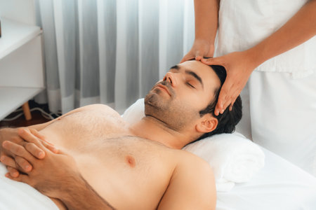 Caucasian man enjoying relaxing anti-stress head massage and pampering facial beauty skin recreation leisure in dayspa modern light ambient at luxury resort or hotel spa salon. Quiescentの写真素材
