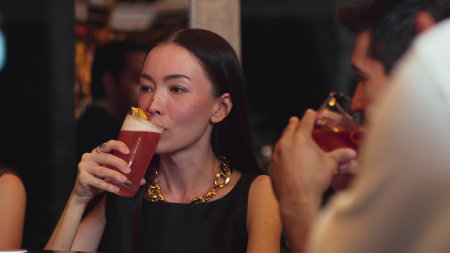 Beautiful woman guest drinking Paloma cocktail while talking with smart couple holding Old fashioned savoring tasty drink at counter luxurious bar with refreshing beverage nightclub party. Vinosity.の写真素材