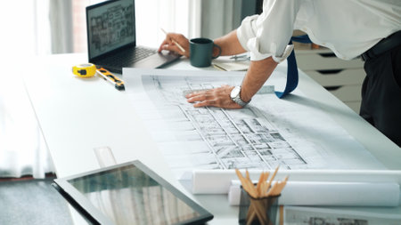 Smart engineer standing and writing idea at blueprint and laptop. Closeup of architect hands...