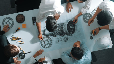 Top down aerial view of smart engineer team working together to design turbine engine. Professional technician discussing about jet engine construction while pointing at part of engine. Alimentation.の写真素材