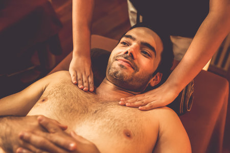 Caucasian man customer enjoying relaxing anti-stress spa massage and pampering with beauty skin recreation leisure in warm candle lighting ambient salon spa at luxury resort or hotel. Quiescentの写真素材