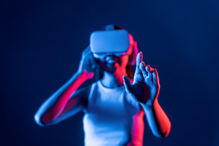 Smart female standing with surrounded by cyberpunk neon light wear VR headset connecting metaverse, futuristic cyberspace community technology. Woman using hand touching virtual object. Hallucination.の写真素材