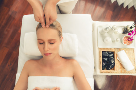 Panorama top view of woman enjoying relaxing anti-stress head massage and pampering facial beauty skin recreation leisure in dayspa modern light ambient at luxury resort or hotel spa salon. Quiescentの写真素材
