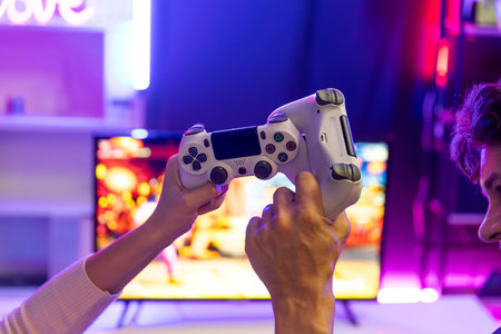 Close up of hands couple or friends joyful player video game on TV using to bring joysticks together...