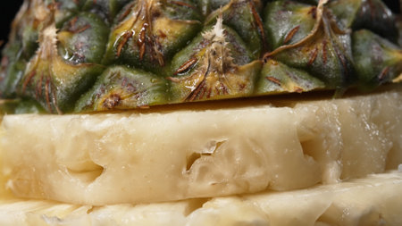 Close up video of fresh pineapple with slice of peel pineapple insert with separated black background. The rough and waxy rind, boasting a crown of spiky green leaves, Food photography. Comestible.の写真素材