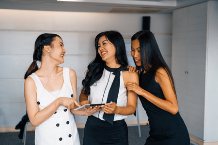 Three Asian women friends having conversation while looking at tablet computer in their hands. Concept of social media, gossip news and online shopping. udsの写真素材