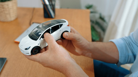 Car design engineer analyze car model prototype for automotive business company at home office. Vehicle designer holding scale car, carefully analyzing looking for any flaw or improvement. Synchronosの写真素材