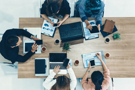 Top view of businessman executive in group meeting with other businessmen and businesswomen in modern office with laptop computer, coffee and document on table. People corporate business team udsの写真素材