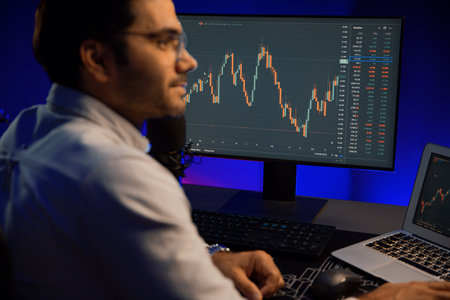 Smart trader businessman concentrating on dynamic stock exchange investment on pc and laptop showing...