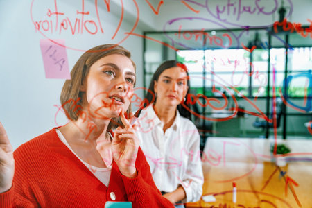 Creative business team brainstorming and sharing marketing idea about start up project by writing down on colorful sticky note at glass board modern meeting room. Working together. Immaculate.の写真素材