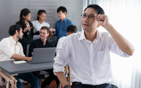 Confidence and happy smiling businessman portrait with background of his colleague and business team working in office. Office worker teamwork and positive workplace concept. Prudentの写真素材
