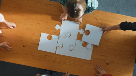 Top down view of skilled business people assemble jigsaw puzzle on meeting table. Group of diverse team working together to solve the puzzle. Represented unity, togetherness, cooperative. Convocation.の写真素材