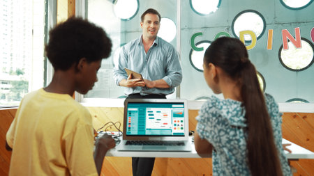 Smart teacher hold tablet while back view student learning engineering code on table with laptop and...