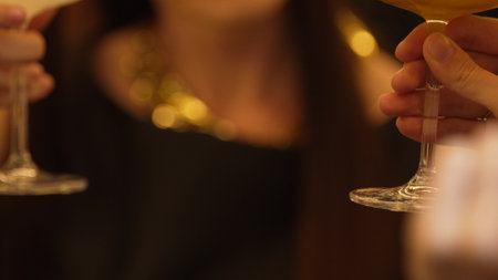 Closeup cropped woman hand making a toast mixed passion fruit smoothie cocktail wearing ring with...