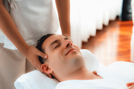 Caucasian man enjoying relaxing anti-stress head massage and pampering facial beauty skin recreation leisure in dayspa modern light ambient at luxury resort or hotel spa salon. Quiescentの写真素材