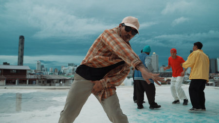 Professional asian street dancer practice B boy dance while multicultural friends at roof top. Young modern dancing group doing hip hop movement. Style,fashion,action. Outdoor sport 2024. Hiphop.の写真素材