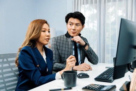 Business Asian coworkers analyzing marketing report project on two screen computer comparing value stock exchange database online report at modern office. Analyzing value investment company. Infobahn.の写真素材