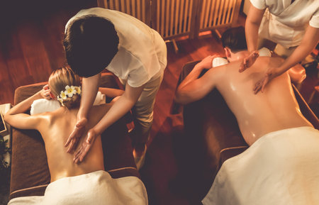 Top view couple customer enjoying relaxing anti-stress spa massage and pampering with beauty skin recreation leisure in warm candle lighting ambient salon spa at luxury resort or hotel. Quiescentの写真素材