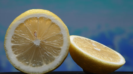 A slice of fresh lemon, bright yellow and vibrantly citric, lies exposed. The flesh, glistening with refreshing juice, reveals its segmented interior. The essence of citrus vibrancy. Comestible.の写真素材