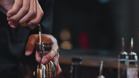 Closeup mixing hand bartender holding jigger to measure juice into shaker design preparation for...