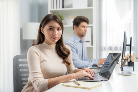 Smiling beautiful woman working on laptop aligning taking note to pose for looking at camera photo shooting portrait profiles business with smart coworker at modern office at morning time. Postulate.の写真素材