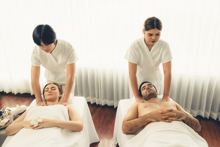 Caucasian couple customer enjoying relaxing anti-stress spa massage and pampering with beauty skin recreation leisure in day light ambient salon spa at luxury resort or hotel. Quiescentの写真素材