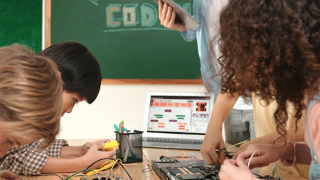 Group of diverse student working together on main board with laptop screen display engineering prompt written while teacher hold tablet and explain online software at STEM technology class. Pedagogy.の写真素材
