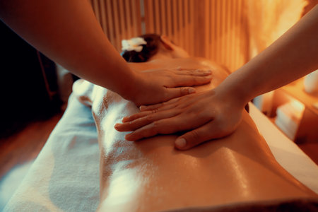 Closeup woman customer enjoying relaxing anti-stress spa massage and pampering with beauty skin recreation leisure in warm candle lighting ambient salon spa at luxury resort or hotel. Quiescentの写真素材