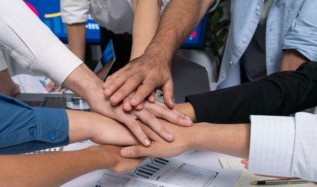 Group of diverse office worker join hand together in office room symbolize business synergy and strong productive teamwork in workplace. Cooperation and unity between business employee. Prudentの写真素材
