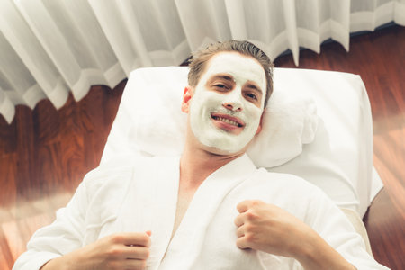 Serene ambiance of spa salon, man customer indulges in rejuvenating with luxurious face cream massage with modern daylight. Facial skin treatment and beauty care concept. Quiescentの写真素材