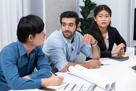 Diverse group of civil engineer and client working together on architectural project, reviewing construction plan and building blueprint at meeting table. Prudentの写真素材